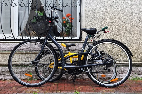 Bicicletas para adultos y niños estacionadas contra la pared contra la ventana . — Foto de Stock