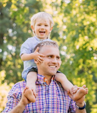 Babası onun omuzlarında oğlu sitiing ile parkta yürüyüş