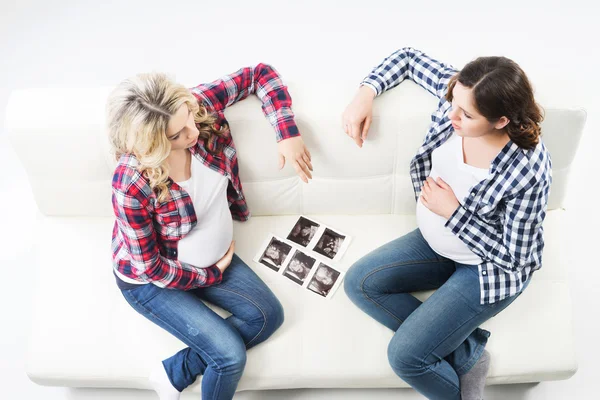 Twee aantrekkelijke zwangere vrouwen echografie foto's kijken — Stockfoto