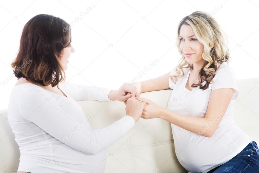 Two beautiful pregnant women holding hands to support each other