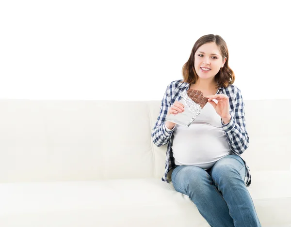 Aantrekkelijke jonge zwangere vrouw met een hapje van chocolade — Stockfoto