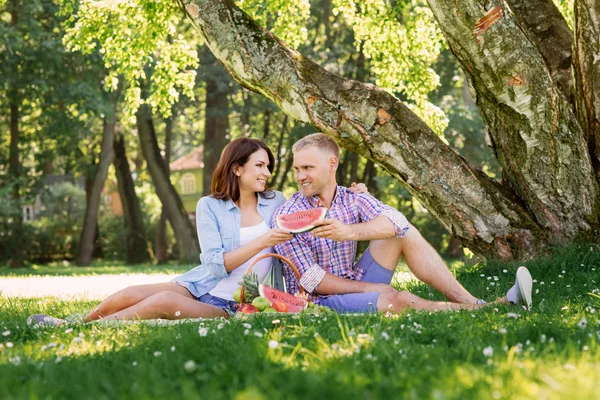 Bella coppia che si diverte a mangiare frutta nel parco — Foto Stock