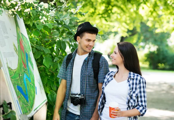 Young couple exploring the park's map — Stock Photo, Image