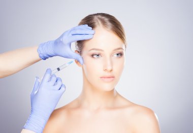 Bir kadının yüzüne botox enjekte eden doktor