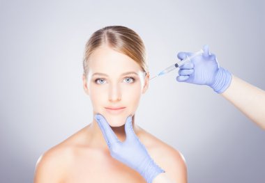 Bir kadının yüzüne botox enjekte eden doktor