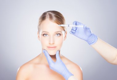 Bir kadının yüzüne botox enjekte eden doktor