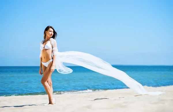 Ung kvinna poserar med blåser silk på stranden — Stockfoto