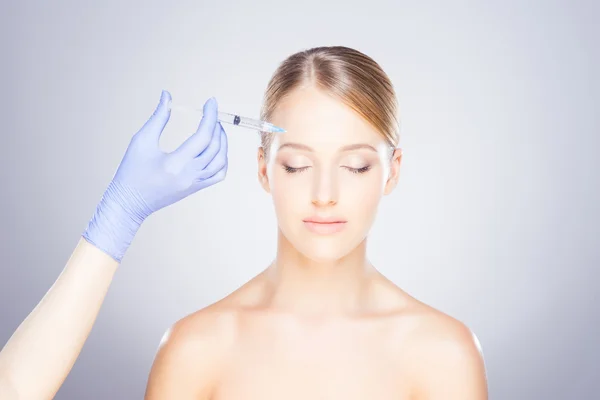 Medico che inietta botox in faccia a una donna Foto Stock Royalty Free