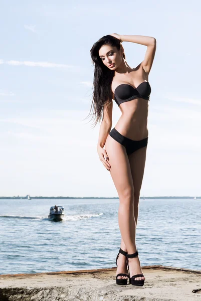 Beautiful and fit fashion model in a swimsuit on a pier — Stock Photo, Image