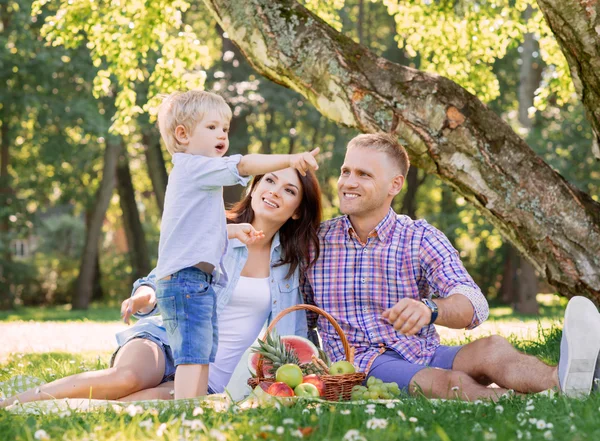 Madre y padre con hijo en un picnic comiendo frutas — Foto de Stock