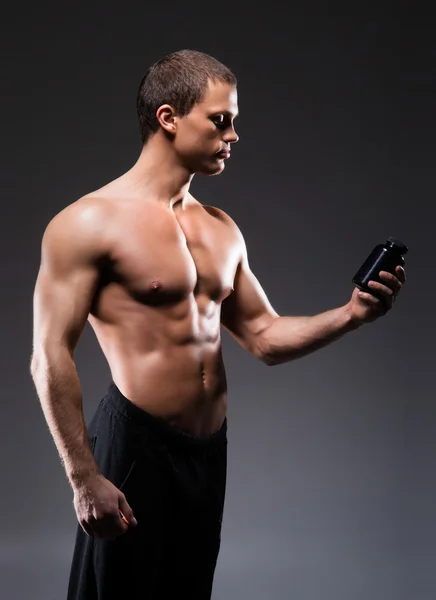 Homme avec une bouteille de suppléments sportifs — Photo