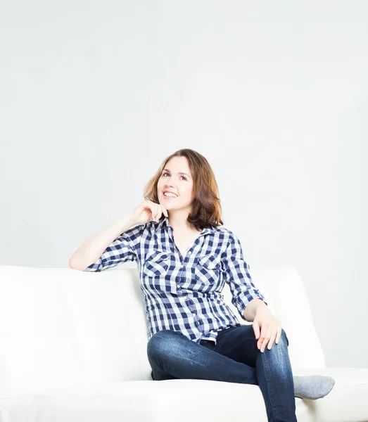 Fille assise sur un canapé à la maison — Photo