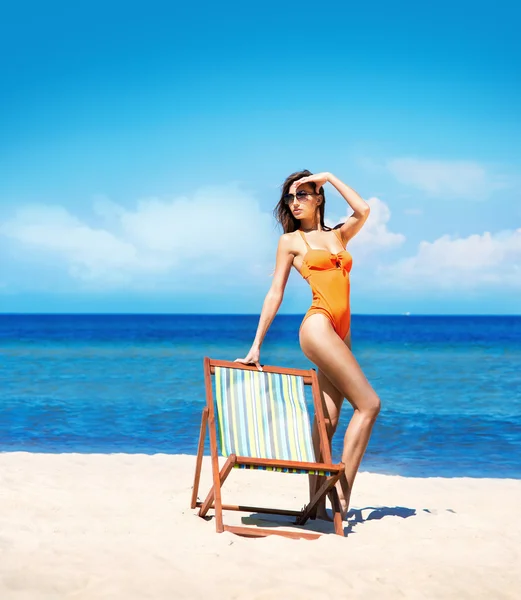 Jong en sexy vrouw in een strandstoel op het strand — Stockfoto