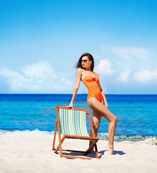 Ung och sexig kvinna i en solstol på stranden — Stockfoto