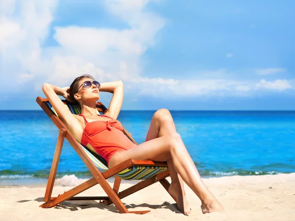 Ung och sexig kvinna i en solstol på stranden — Stockfoto