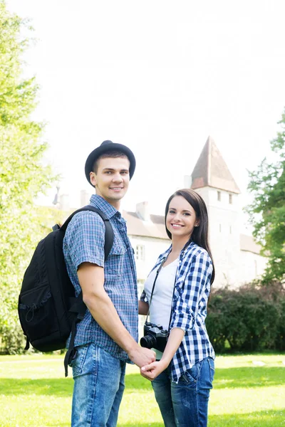 Beautiful traveling couple holding hands in the park — Stock Photo, Image