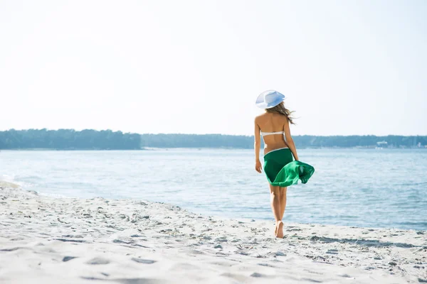 Jong en sexy vrouw poseren in een hoed op het strand — Stockfoto