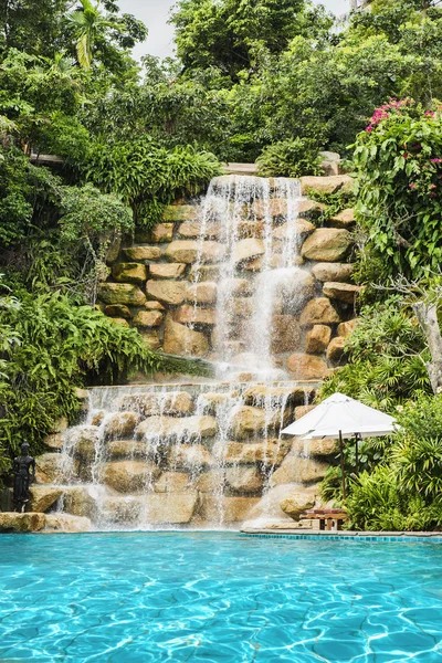 Luxury swimming pool nearby tropical forest and waterfall — Stock Photo, Image