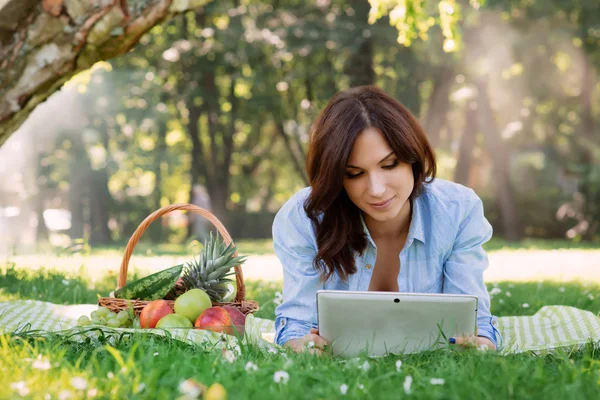 Giovane bruna essere dipendente dal tablet su un picnic in p — Foto Stock