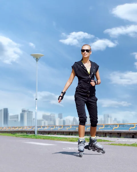 Jovem e apto mulher patinando em patins — Fotografia de Stock