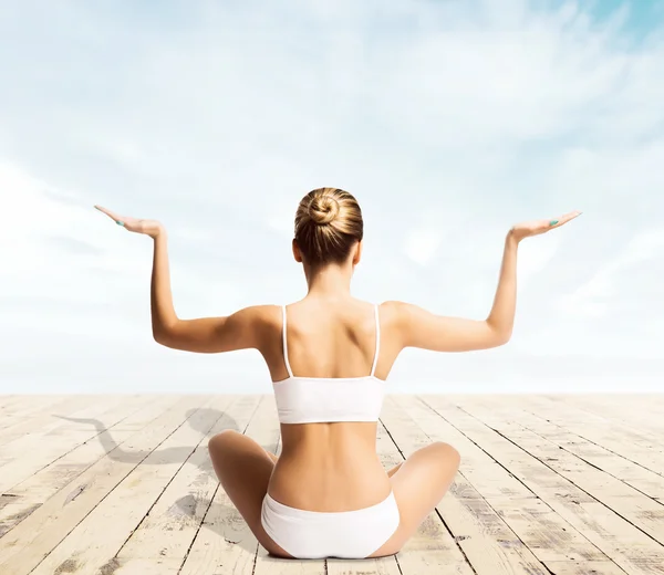 Menina jovem, esportiva e bonita meditando em um cais — Fotografia de Stock