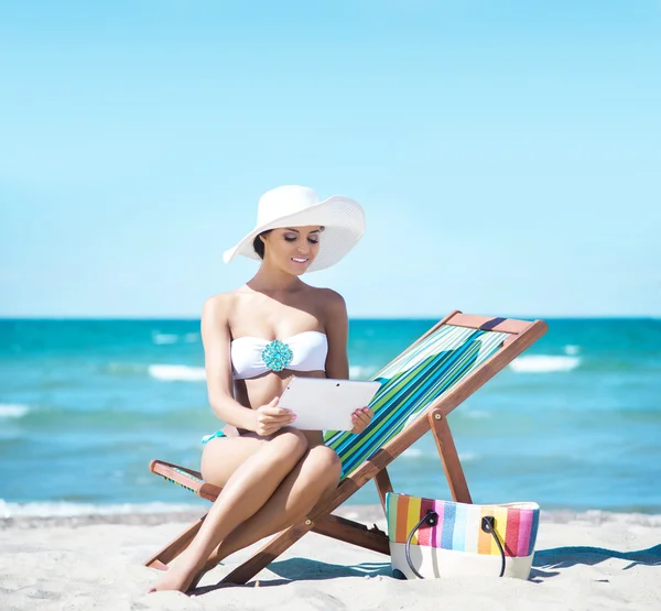 Een vrouw met een tabletcomputer op het strand ontspannen — Stockfoto