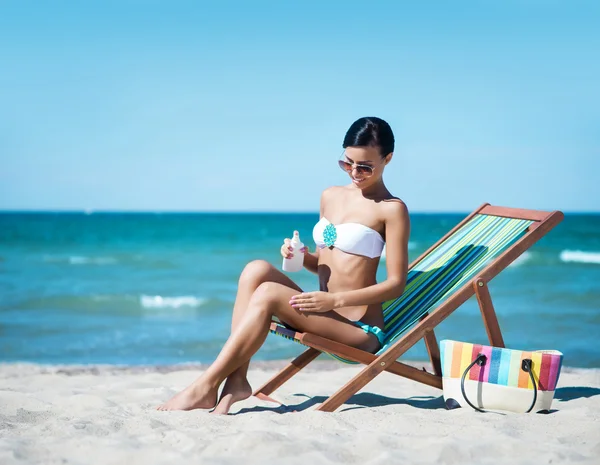 Młoda i seksowna kobieta przy użyciu krem do opalania na plaży. — Zdjęcie stockowe