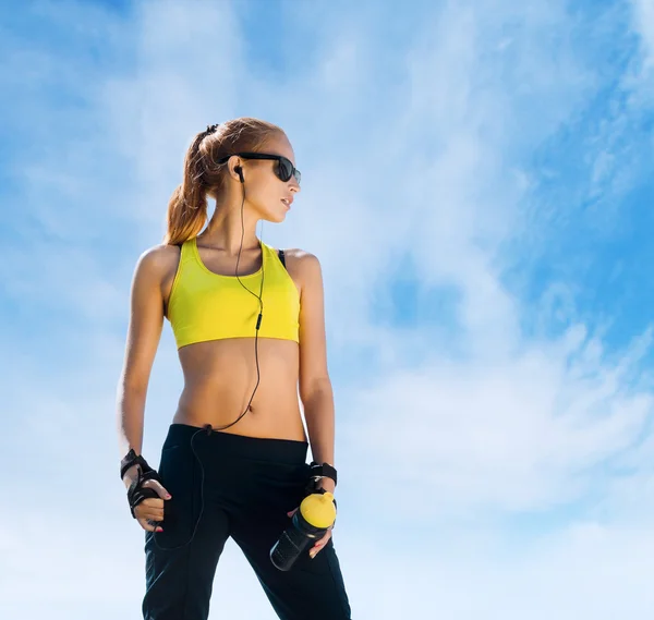 Mujer joven y en forma en ropa deportiva sobre un fondo del cielo — Foto de Stock