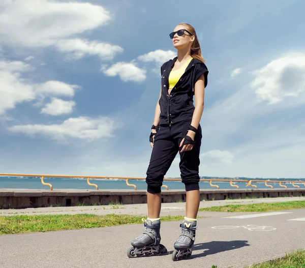 Jovem e apto mulher patinando em patins — Fotografia de Stock