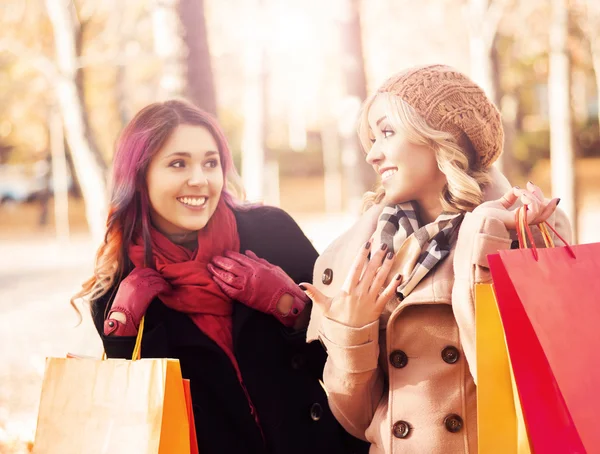 Beautiful girls walking in park with colorful bags — Stock Photo, Image