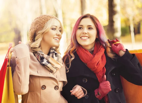 Belle ragazze a piedi nel parco con borse colorate — Foto Stock