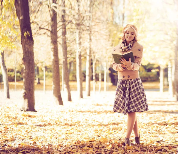 Молодая женщина читает книгу в осеннем парке — стоковое фото