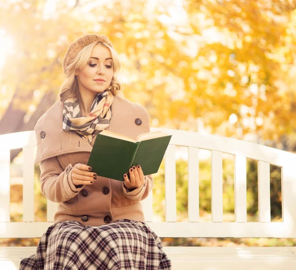 Νεαρή γυναίκα διαβάζοντας ένα βιβλίο σε ένα Φθινοπωρινό πάρκο — Φωτογραφία Αρχείου