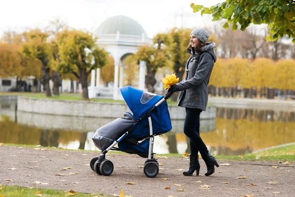 Mor promenader med baby barnvagn — Stockfoto
