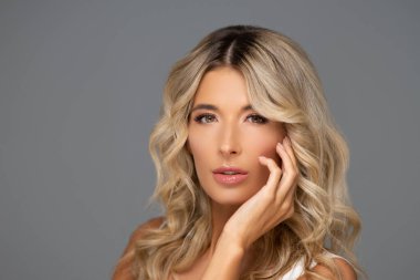 Gri arka planda genç ve güzel bir kadının stüdyo portresi.