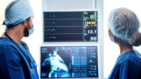 Médecins professionnels travaillant en médecine d'urgence. Portrait du chirurgien et de l'infirmière dans des masques protecteurs effectuant une opération chirurgicale. — Photo