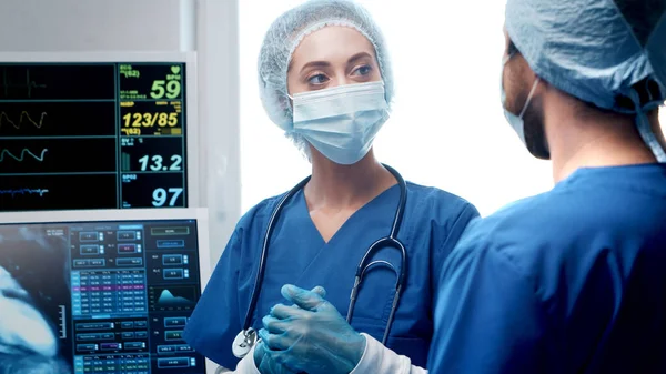 Médecins professionnels travaillant en médecine d'urgence. Portrait du chirurgien et de l'infirmière dans des masques protecteurs effectuant une opération chirurgicale. — Photo