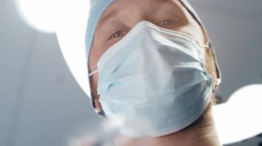 Doktorların elindeki oksijen maskesinin birinci şahıs görüntüsü. Hasta koruyucu maskeli cerrahın yüzüne bakıyor. Anestezi ve narkoz..
