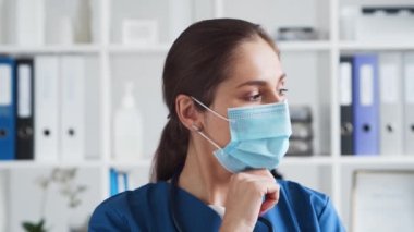 Hastane ofisinde profesyonel tıp doktoru koruyucu maskeli genç ve çekici bir kadın doktorun portresi. Tıbbi konsept.