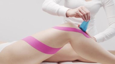 Terapist kadın vücuduna kinesio bandı uyguluyor. Fizyoterapi, kineziyoloji ve iyileşme tedavisi.