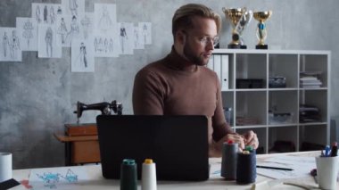 Genç ve yetenekli moda tasarımcılarının işyeri. Terzi şık çatı katında tek başına çalışıyor. Kıyafet çizimleri kullanıyor..