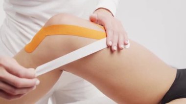 Terapist kadın vücuduna kinesio bandı uyguluyor. Fizyoterapi, kineziyoloji ve iyileşme tedavisi kavramları.