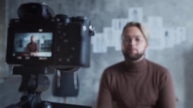 Genç moda blogcusu kamera kullanarak kıyafet tasarımı hakkında video blogu kaydediyor. Modern çatı katındaki iş yerinden yetenekli stilist akışı..