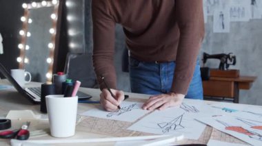 Genç ve yetenekli moda tasarımcılarının işyeri. Terzi şık çatı katında tek başına çalışıyor. Kıyafet çizimleri kullanıyor..