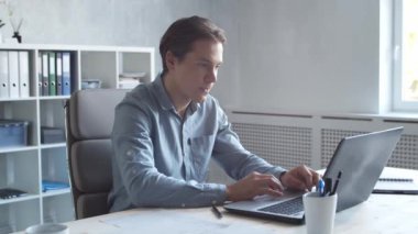 Modern ofiste bilgisayar kullanarak çalışan bir iş adamı. Genç ve kendinden emin iş adamının işyeri..