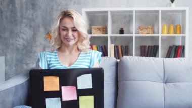 Genç ve çekici bir kadın evde dizüstü bilgisayar kullanarak çalışıyor. Kanepede serbest çalışan ya da öğrenci. Kilitleme kavramı.