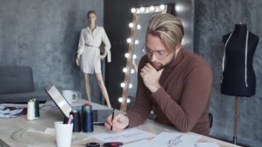 Genç ve yetenekli moda tasarımcılarının işyeri. Terzi şık çatı katında tek başına çalışıyor. Kıyafet çizimleri kullanıyor..