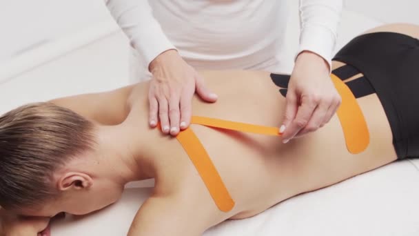 Therapeut Brengt Kinesio Tape Aan Vrouwelijk Lichaam Fysiotherapie Kinesiologie Herstelbehandelingsconcepten — Stockvideo