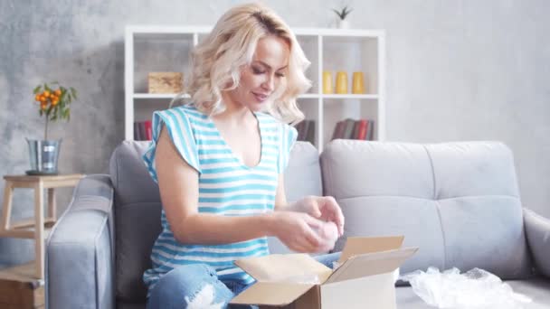 Genç Mutlu Bir Kadın Evdeki Kanepede Oturan Paket Kutusunu Açıyor — Stok video
