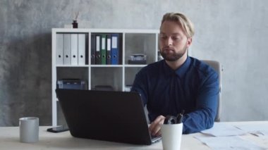İşadamı bilgisayar teknolojisini kullanarak modern ofiste tek başına çalışıyor. Genç ve kendinden emin iş adamının işyeri..